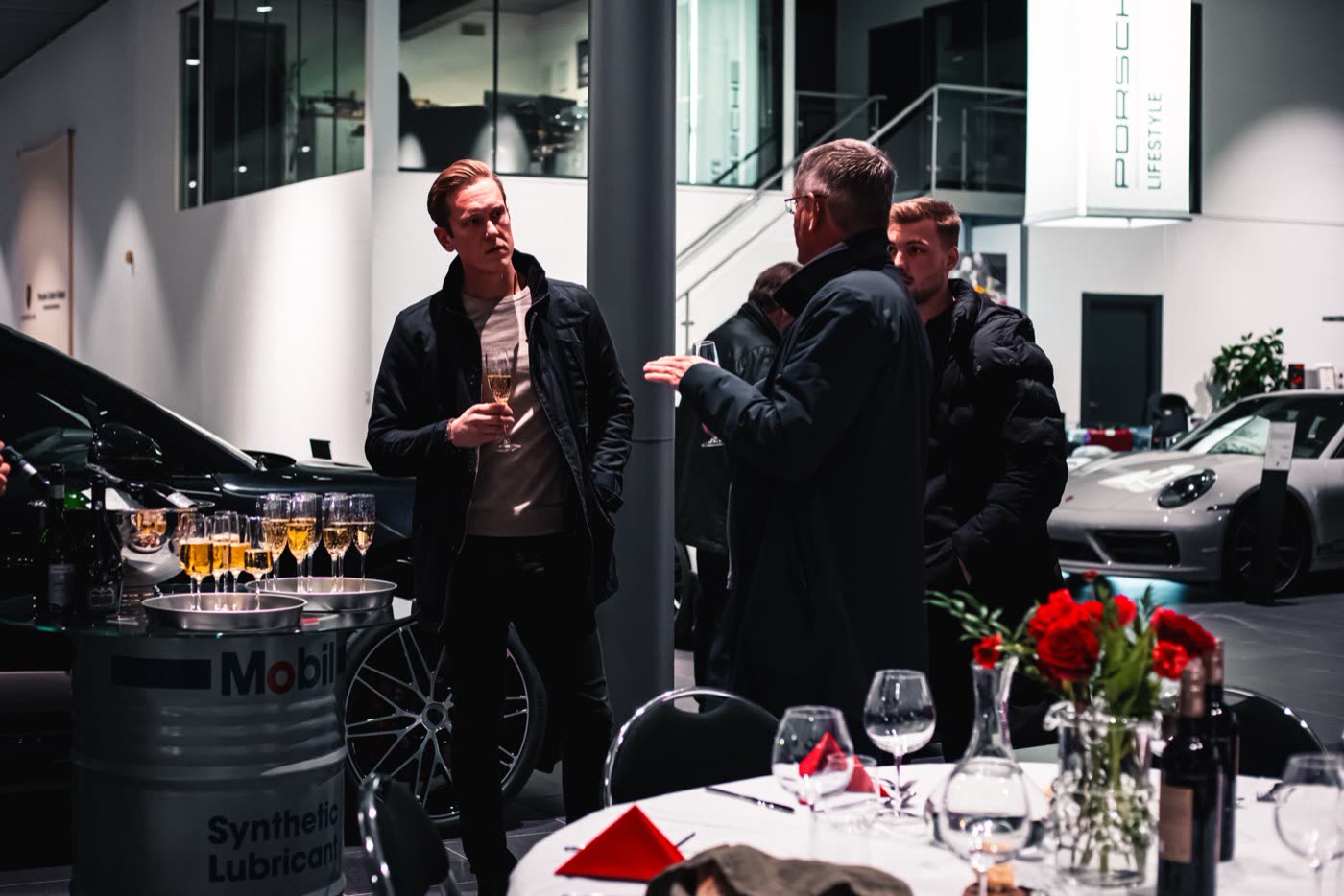 Three guests greeting host at Porsche Center Kalmar entrance during Macan Electric reveal